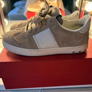 Valentino flycrews  - Snygga sneakers från Valentino Garavani i beige mocka med vita skinnpaneler och coola nitar på sulan. Möts gärna upp i Stockholm.