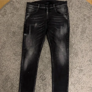 Svarta dondup jeans med slitningar - Säljer ett par svarta dondup jeans med slitningar och blekta detaljer. Storlek 31 och är i riktigt bra skick.