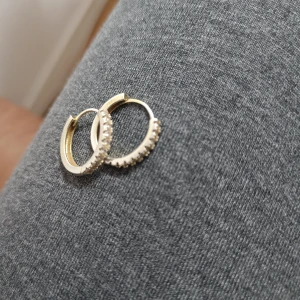  creoler med stenar - Säljer ett par snygga creolörhängen med glittrande vita stenar längs framsidan. Runda och stilrena, märkta med 925 vilket betyder att de är i äkta silver. Perfekta för dig som gillar klassisk men ändå trendig stil.