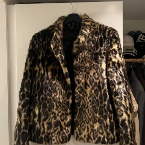 Leopardmönstrad pälsjacka Rockandblue - Säljer en snygg leopardmönstrad pälsjacka från Rockandblue i storlek 36. Jackan har fluffig fuskpäls, klassisk krage och knäppning framtill. Färgerna är brun, svart och beige med coolt djurmönster. Perfekt statement-plagg för dig som vill sticka ut.