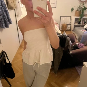 Vit bandeau topp med volang - Säljer en söt vit bandeau topp med smockad överdel och volang nertill. Perfekt till sommaren och fungerar även som kjol!! ❣️❣️