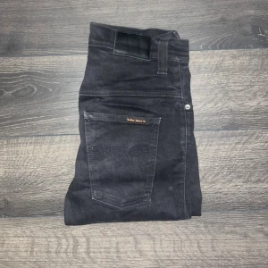 Nudie jeans  - Svarta herr jeans från Nudie Jeans med klassisk femficksdesign och smal passform. Jeansen har svarta sömmar. Midja 37cm, längd 88cm. OBS de är uppklippta (öppna benslut), storleken motsvarar mer W30 och L28 heller L30. Ifall det inte finns någon bild i annonsen där jag bär plagget så är det för att jag ej kan ha storleken heller passformen, så kolla måtten för storlek och googla på modellnamnet för passform 😉S3