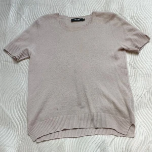 Ljus rosa kashmirtröja från Lisa Yang - Ljus rosa tröja i 100% kashmir från Lisa Yang. Modellen har korta ärmar, rund hals och ribbade muddar vid ärmslut och nederkant. 