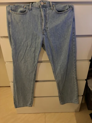 Jack & Jones ljusblå jeans, storlek 32 - Ljusblå jack and Jones jeans med klassisk femficksdesign och raka ben. Jeansen har knappgylf. Tillverkade i slitstark bomull med en tidlös look som funkar till många stilar.