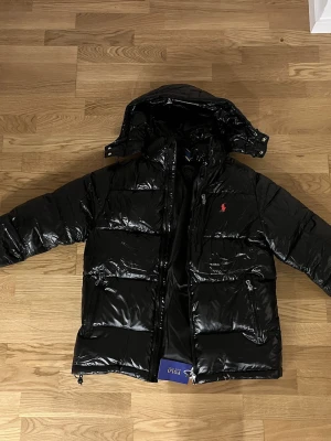  Polo Ralph Lauren jacka - Säljer denna jacka för att den inte passar mig så vill hälst bli av med den. Den har aldrig vart använd! Och har qr kåd till deras hemsida. Sedan så går luvan av med en dragkedja som inte syns som kan vara skönt om luvan kan störa!!