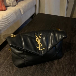 Svart läder väska me guld logga - Pris kan diskuteras vid snabb affär då ja ska åka iväg 31 dec. Använd men i bra skick. Behövt knyta kedjan inne i väskan så att axelbandet ska vara i rätt storlek. 