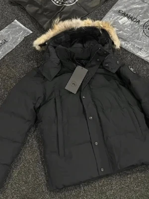 Canada goose dunjacka M - Svart dunjacka från Canada Goose med fluffig päls på huvan och snygga detaljer som knappar och dragkedja. Jackan har lång ärm, patch på armen och är perfekt för kalla dagar. Stilsäker och varm, med klassisk pufferlook och coolt märke.