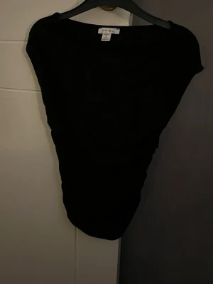 Svart ärmlös topp  - Säljer en svart, enkel och stilren topp. Modellen är ärmlös med bred halsringning och rak passform. Perfekt att matcha med jeans eller kjol för en clean look.