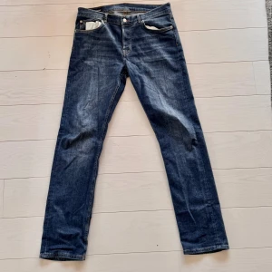 Blå jeans från J.Lindeberg straight fit - Snygga blå jeans från J.Lindeberg med klassisk femficksdesign och kontrastsömmar. Modellen har rak passform och normal midja, vilket ger en clean och tidlös look. Jeansen är tillverkade i mjukt denimtyg som sitter skönt hela dagen.