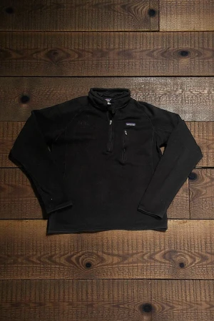 Svart fleece tröja  Patagonia - Svart fleece tröja från Patagonia med half zip. Tröjan har en bröstficka med dragkedja och är långärmad. Perfekt för kyliga dagar och outdoor vibes. En diskret svart logga till vänster är broderad.(se bild)