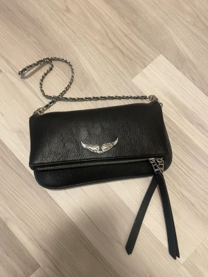 Svart axelväska med kedja - Hej! Säljer nu min väska då den inte kommer till användning längre! Väskan är köpt från Amazon och är därför inte äkta men ska föreställa Zadig & Voltaire.