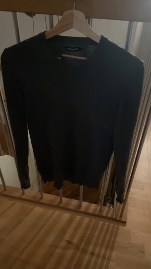 Merinoull J.Lindeberg tröja - Snygg svart stickad tröja från J.Lindeberg i storlek M. Tröjan har rund hals, långärmade ärmar och diskret JL-logo broderad på bröstet. Perfekt för dig som gillar stilrena och klassiska plagg med en modern touch.