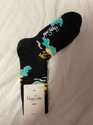 svarta strumpor med mönster (unisex) - helt oanvända, svarta strumpor med palmträdsmönster från märket happy socks! storlek 36-40, unisex.