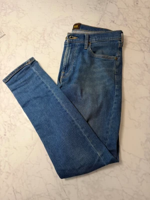 Blå Lee Luke jeans W30 L32 - Säljer ett par klassiska blå Lee Luke jeans med snyggt tapered snitt och normal passform. 