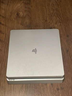 PlayStation 4 Slim Silver Edition - PlayStation 4 Slim Silver Edition i gott skick. Konsolen har några ytliga repor på ovansidan men fungerar utmärkt. Utrustad med HDMI, USB och nätverksport. Perfekt för spel och underhållning. Konsol ingår inte men strömkabel och hdmi ingår