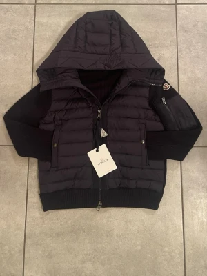 Navy blue Down Zip-Up Cardigan Från Moncler - Säljer en Navy Down Zip-Up Cardigan Från Moncler. Bilderna ser den ut som den är svart men är i självavärket marineblå. Storlek M men passar bättre som S. Nfc funkar inte. Nyskick. Priset är inte hugget i sten.
