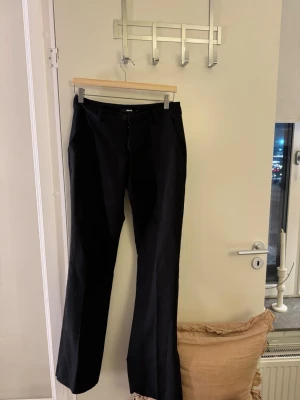 Svarta bootcut kostymbyxor - Säljer ett par svarta låg midjade kostymbyxor med bootcut passform och med slits. Dom är ifrån Bikbok i storlek 38. Har dock spretat upp dom där nere för jag då tyckte dom var förkorta. Men dom är som nya har använt dom 2 gånger så de är inte slitet nere på byxorna eller i dåligt skick ☺️☺️