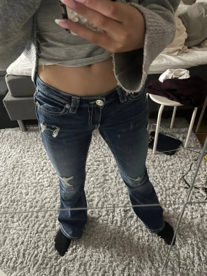 Low waist Bootcut jeans från Gina Tricot XS - Säljer ett par mörkblå bootcut jeans från Gina Tricot i storlek XS. Jeansen har slitna detaljer, låg midja och kontrastsömmar. Bakfickorna har broderade mönster och passformen är loose med utsvängda ben. Perfekta för en avslappnad och trendig look. Aldrig använda endast provade