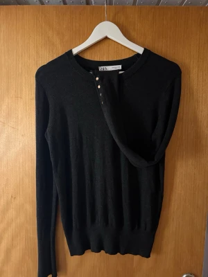Svart stickad kofta från Zara - Säljer en mörkgrå  stickad kofta från Zara i storlek M. Tröjan har rund halsringning, långa ärmar och fyra snygga guldfärgade knappar vid ärmsluten. Perfekt till höst och vinter för en clean och stilren look. Kommer ej till användning 🌸Liten i storlek, sitter mer som S