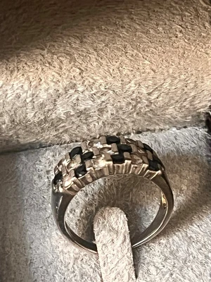 Silvrig ring med rutigt mönster - Säljer en unik silvrig ring med rutigt mönster i svart och silver. Ringen har en bred design och en cool, upphöjd struktur som ger den en modern känsla. Perfekt accessoar för dig som vill sticka ut lite extra.