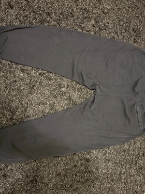 Svarta mjukisbyxor från Nike - Svarta mjukisbyxor från Nike med klassisk logga på vänster ben. Byxorna har resår i midjan med snörning och muddar vid bensluten. Tillverkade i mjukt bomullsmaterial för maximal komfort. Perfekta för chill eller träning.