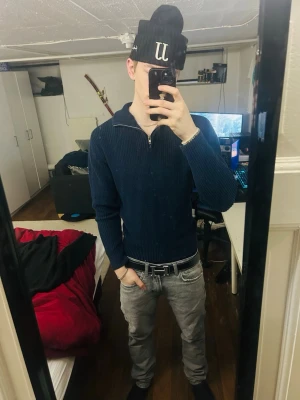 Mörkblå stickad tröja med half zip - Säljer en mörkblå stickad tröja med ribbad struktur och half zip-dragkedja vid halsen. Tröjan har lång ärm och en klassisk, lite loose passform. Perfekt för lager-på-lager och chillare dagar.