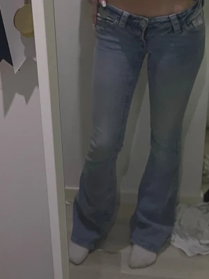 Bootcut ljusblå jeans - Säljer ett par ljusblå bootcut jeans med låg midja. De har rosa detaljer på bakfickorna 🩷 storlek xs