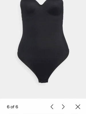 Svart body med tunna axelband - Säljer en svart body med tunna, justerbara axelband och formpressade kupor. Bodyn har en enkel och stilren design med mjukt material som sitter tight mot kroppen. Perfekt att styla till jeans eller kjol för en clean look. Den är från Dorina och väldigt fin  men passar inte mig så därför jag säljer min body och har aldrig andvänt den så prislapparna är kvar😊