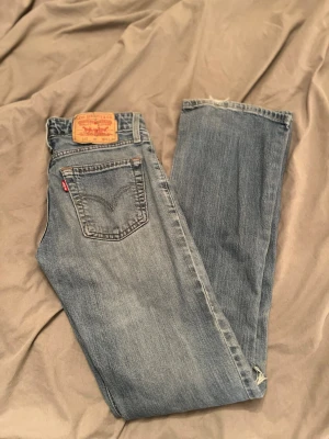 Blåa bootcut jeans från Levis  - Lågmidjade bootcut jeans från Levis med ett hål vid knät. Snygga och bra passform. 