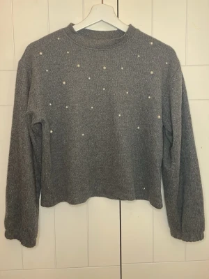 Grå stickad tröja med pärlor från Zara - Tröjan har fått något slags av fläckar bakom lappen, skulle gissa på att det går bort i tvätten.