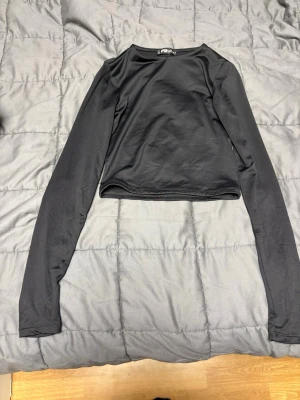 Svart långärmad topp från FB Sister - En enkel och stilren svart långärmad topp från FB Sister i storlek XS. Toppen har en rund halsringning och är gjord i ett mjukt, stretchigt material 
