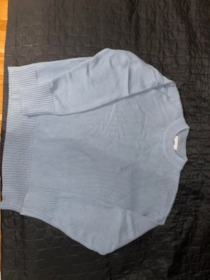 Ljusblå stickad tröja från Ami - Säljer en ljusblå stickad tröja från Ami Alexandre Mattiussi. Tröjan har ribbade muddar, rund hals och ett diskret broderat hjärta med A på bröstet. Tillverkad i mjuk bomull och perfekt för dig som gillar stilrena plagg med en twist. Nästan aldrig använd.