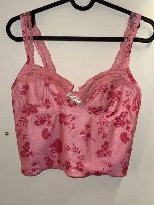 Rosa blommig crop top med spetsdetaljer - Söt rosa crop top med blommigt mönster i mörkare rosa toner. Super söt! Passar till S. 