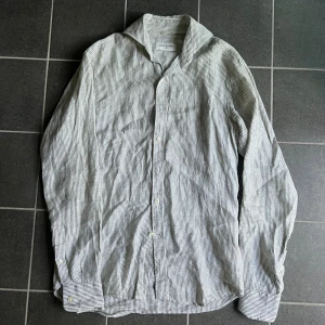 Randig linneskjorta från John Henric - Snygg randig linneskjorta från John Henric i vitt och grönt. Skjortan har klassisk krage, knäppning framtill och långa ärmar med manschett. Tillverkad i 100% linne, perfekt för en stilren look. Passar dig som gillar enkel men fräsch stil.