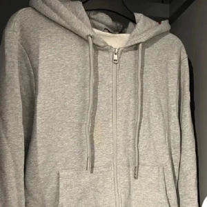 Moncler hoddie - Snygg grå hoodie från Moncler med hel dragkedja, säljer denna feta tröja för är sugen på något annat det är storlek L men passar bäst M skulle jag säga priset är inte fast men rimligt pris skriv gärna om ni har frågor