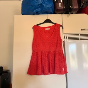 Röd ärmlös blus Odd Molly - Supersöt korallrosa blus från Odd Molly med broderade hålmönster och v-ringning. Modellen är ärmlös och har en volangkant nedtill som ger en flowy känsla. Perfekt för varma dagar och enkel att styla med jeans eller kjol. Storlek 1 som enligt deras storleksguide motsvarar en storlek S. Mycket fint skick, jag hittar inga synliga anmärkningar eller defekter. Färgen är dock inte som på bilderna. Ljusare i verkligenen. Mer en korallrosa. 