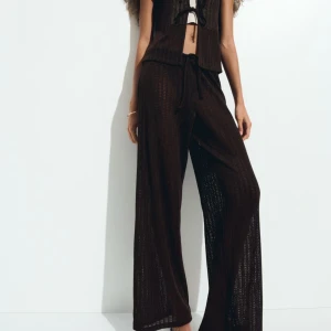 Bruna stickade wide byxor med snörning + tröja  - Mörkbruna stickade byxor med breda ben och avslappnad passform. Byxorna har snörning i midjan och är tillverkade i ett luftigt stickat material som ger en cool och trendig look. Perfekta för dig som gillar en chill och stilren vibe. I ett set. 