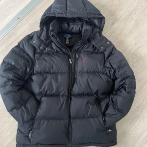 Ralph Lauren Jacka (Barn XL=Herr S) - Säljer en Ralph Lauren jacka som är i bra skick, men det finns några små hål i jackan som ni kan se i bilden! Hållarna har kommit från gamla ägaren när han har skjutit raketer under ny år! Hållarna är inte så lätt att upptäcka om du bara går runt med den!  Men nu med positiva grejerna av jackan, är ju att den är jätte varm under vintern och passar till nästan allt vad har på dig!👌🏼 (På jackan står det XL pågrund av att det är en barn storlek men XL på barnstorlek motsvarar Storlek S i herr❗️) (Gam