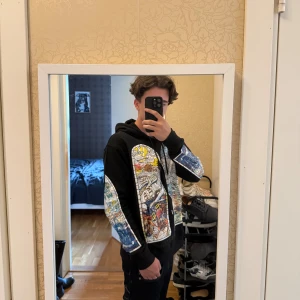 Who Decides War hoodie - Säljer en svart hoodie från Who Decides War i storlek S. Tröjan har en unik färgglad grafisk print på bröstet och ärmarna, dragkedja framtill och huva med snörning. 