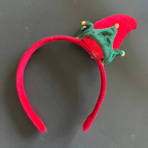 Rött diadem med tomteluva och bjällror - Juligt rött diadem med en liten tomteluva i röd och grön sammet, dekorerad med små guldfärgade bjällror. 