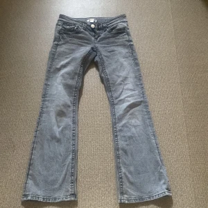 Grå bootcut jeans Gina Tricot 146 - Snygga grå jeans från Gina Tricot i storlek 146. Modellen har bootcut-ben, klassiska fem fickor och knäppning fram. Jeansen är i mjukt denimtyg och har en cool, lite tvättad look. Perfekta för dig som gillar en avslappnad men trendig stil.