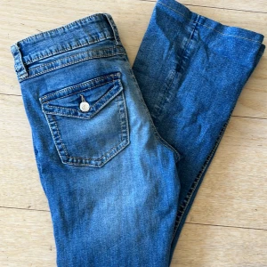 Blå jeans från Gina Tricot, storlek 170 - Säljer ett par klassiska blå jeans från Gina Tricot i storlek 170. Jeansen har en snygg tvätt, raka ben och coola detaljer som ficklock med knapp bak. Perfekta till vardags och lätta att matcha med allt. Materialet är mjukt jeans-tyg i bomull.säljer för att dom inte passar mig🩵