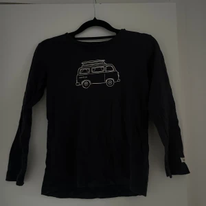 Svart långärmad tröja från Newbie - Svart långärmad tröja från Newbie med ett vitt tryck av en van på bröstet. Tröjan har rund halsringning och är tillverkad i mjuk bomull.