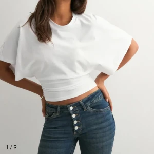 Vit croppad topp från Nelly XS - Säljer en vit croppad topp från Nelly i storlek XS. T-shirten har korta, vida ärmar och en tightare midja som ger en snygg siluett. Tillverkad i mjuk bomull med rund halsringning. Aldrig använd 🩷