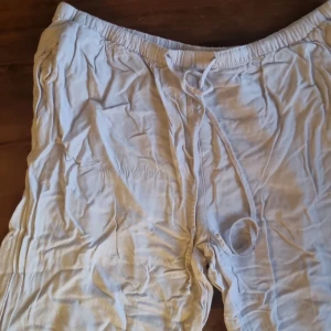 Vita linnebyxor från Gina Tricot L - Luftiga vita linnebyxor från Gina Tricot i storlek L men dom sitter som storlek M. Byxorna har resår i midjan och snörning för extra komfort. Perfekta för varma dagar med sin lätta känsla och avslappnade passform. Men dom har en missfärgning på snöret som säkert går att bleka bort.