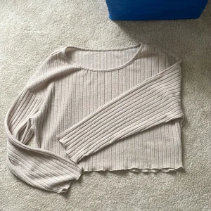 Beige ribbad tröja från SHEIN - Superfin beige ribbad tröja från SHEIN i storlek M. Tröjan har lång ärm, croppad passform och rund halsringning. Perfekt till lager-på-lager och enkel att matcha med jeans eller kjol. Mjuk och stretchig i materialet för extra komfort.