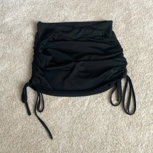 Svart och vit kortkjol från SHEIN - Två snygga korta kjolar från SHEIN i svart och vitt. Kjolarna har snörning i sidorna och är gjorda i ett stretchigt syntetmaterial. Perfekt för dig som gillar en tight passform, säljer dessa både en och en men även som paket! (En kjol 25kr) och (paketpris 40kr)🩷