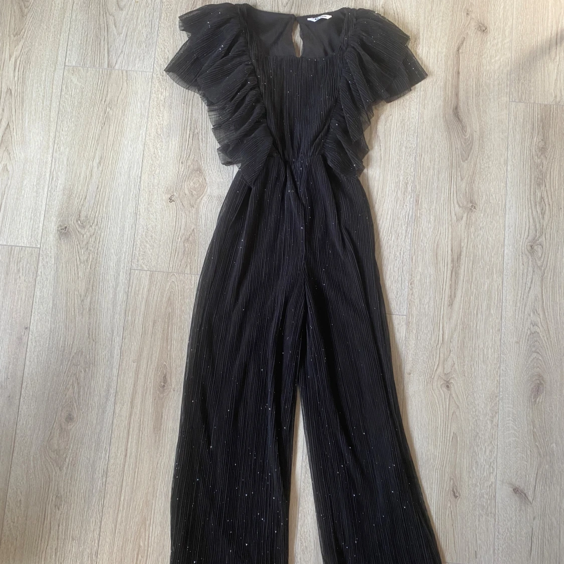 Svart glittrig byxdress med volanger