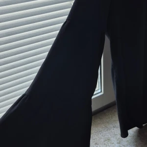 Svart blus med volang - Hej fina tjejer. Jag vill sälja  en svart blus  med  långa ärmar och volangdetaljer. Blusen har en lätt rynkad halsringning och är tillverkad i ett tunt, flowy material som ger en snygg siluett. Den är size M medium men passade för mig som tar small för det mesta. 