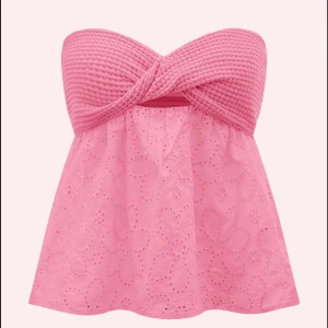 Rosa bandeau tubtopp med broderade blommor - Ser bättre ut på än vad dom gör på de sista två bilderna. Supersöt rosa bandeau tubtopp med virkad twistad överdel och broderade blommor på den vida nederdelen. Toppen är axelbandslös och har en luftig känsla, perfekt för varma dagar. Materialmix av stickad överdel och bomullstyg nedtill.